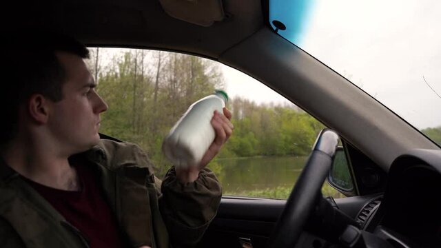 man drinks kefir while sitting in the car