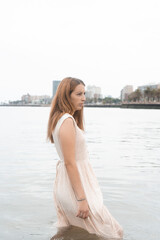 Hispanic female in a beige sundress is standing in the water