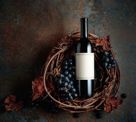 Bottle of red wine with grapes and dried vine leaves on an old rusty background. Top view with copy space.