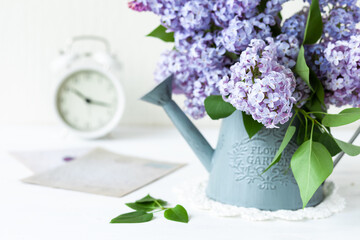 Beautiful fresh violet lilac bouquet in metal watering can. Greeting card for Mother's day, Saint Valentine's Day, 8 march, Women's day. White background, close up