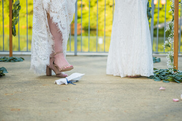 Pair of lgbt women lesbians stomping on glass for Jewish wedding ceremony tradition
