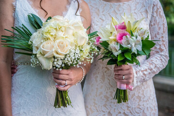 Lgbt lesbian women brides holding bouquets side by side - same sex wedding