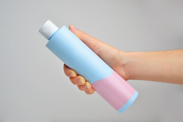 Hand holding shampoo bottle isolated on white background. Blu pink plastic cosmetics container for shampoo. Cosmetics mockup for branding. Beauty makeup product. Space for Text. Mockup shampoo bottle.
