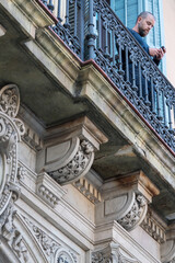 Man standing on the balcony on historical building holding his phone