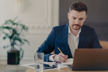 Young handsome executive manager working in front of laptop at home office