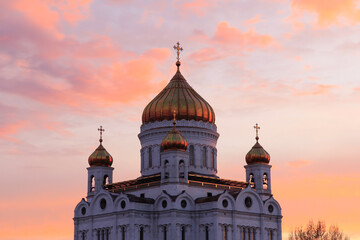 Fototapeta na wymiar Orange sunset in Moscow: the view of the Cathedral of Christ the Savior and the pedestrian Patriarshy Bridge.