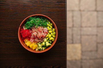 Hawaiian tuna poke bowl with vegetables on wooden table
