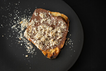 grilled toast with chocolate and grated walnuts, on a black ceramic plate
