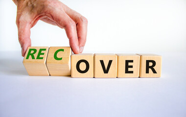 Time to recover symbol. Businessman turns wooden cubes and changes the word 'over' to 'recover'....
