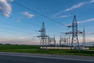 Silhouette of the high voltage electric pylon towers on the background of beautiful evening clouds