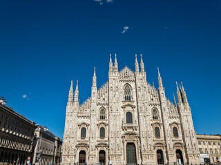 View of the Milan Cathedral and the square. Duomo di Milano. Overview of the facade of the cathedral in white marble. Buttresses, pinnacles and spiers. Statue of the Madonnina. Lombardia. Italy