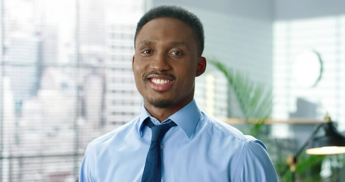 Close up portrait of young joyful male specialist looking at camera and smiling. Positive emotions. African American handsome cheerful employee at workplace, cabinet, businessman concept