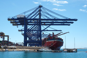 Fototapeta na wymiar Container tanker ship anchored next to loading - unloading crane facility in Mediterranean logistics port