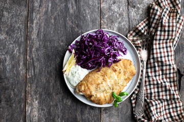 Baked fish steak with red cabbage salad on wooden table