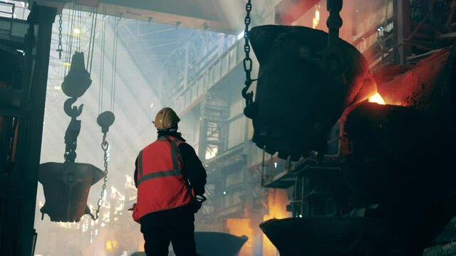 Metallurgical factory interior. Metallurgical plant unit with a steel worker in protection wear