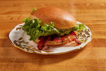 BLT sandwich served on an white ornate plate with gold details on a wooden surface