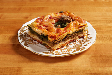 Spinach and mushroom lasagna served on a white plate with gold ornate details
