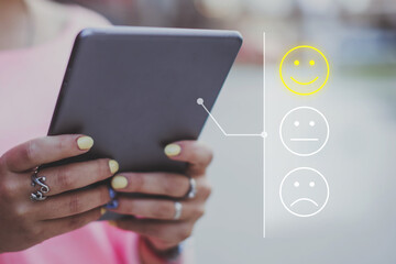 Good mood concept made of emoticon and rating. The girl puts grades on the Internet using a tablet.