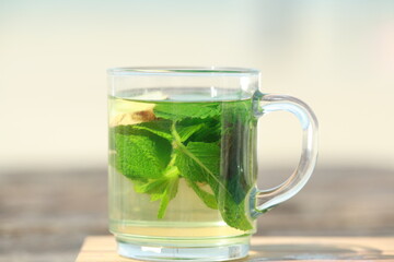 Peppermint tea with green leaves in front of a beach