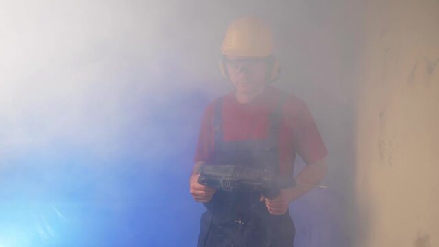 A builder emerges from a cloud of smoke with a perforator in his hand