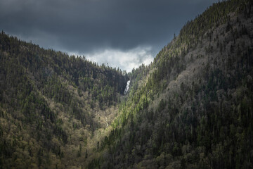 Fototapeta premium Amazing photo of a waterfall coming from the top of a mountain in Jacque cartier national park, Quebec, Canada