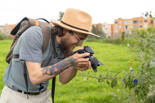 photographer with hat and glasses smiling while taking pictures of flowers and the nature