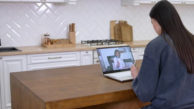 Young woman in homel wear talking by video call with cheerful female doctor therapist while staying at home, patient explaining symptoms through video conference on laptop. Telemedicine concept
