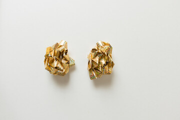 crumpled gold and white gift bows arranged on a plain white-grey ground - photographed from above in a flat lay composition 
