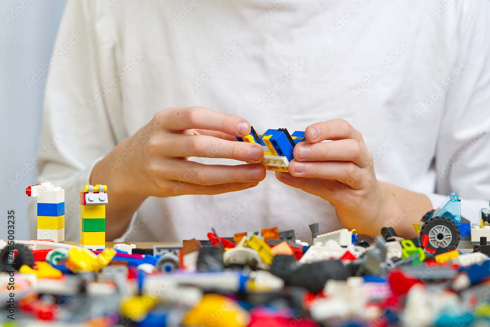 Poster close up of child's hands playing with colorful plastic bricks at the table. development of fine mot