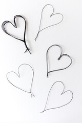 five isolated craft wire (painted black) hearts on white - photographed from above in flat lay composition