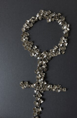 old, worn, recycled square pyramidal metallic studs or spikes arranged in the shape of a female...