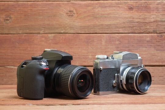 Modern and old professional photo camera with telephoto lens on wooden planks. photographer