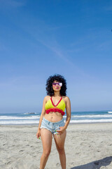 beautiful young Mexican woman with curly hair walking on the beach. vacation concept