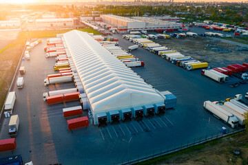 Logistics park with warehouse and loading hub. Semi-trailers trucks stand at ramps and wait for...