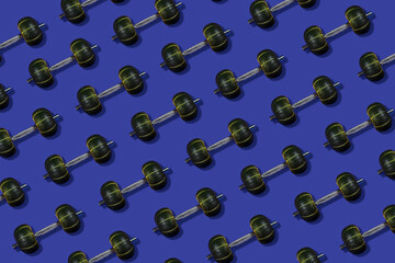 Creative pattern made of dumbbells with a weight in the form of pumpkins, cyan background, healthy lifestyle and sport concept