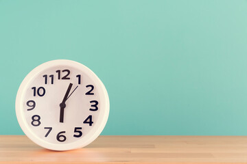 Retro alarm clock on wooden table with green background, vintage style