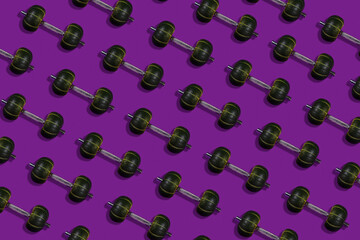Creative layout made of dumbbells with a weight in the form of pumpkins, purple background, healthy lifestyle and sport concept