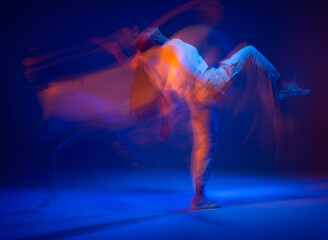 Dancing sportive female in colorful neon light. Expressive contemporary dance. Studio photography with long exposure