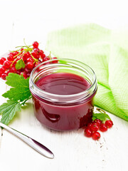 Jam of red currant in jar on wooden board