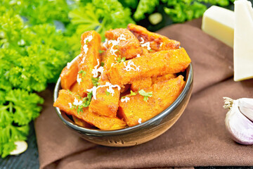 Pumpkin fried with spices in bowl on dark board