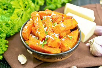 Pumpkin fried with spices in bowl on wooden board