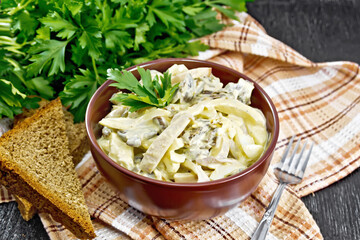 Salad with squid and champignons in bowl on dark board