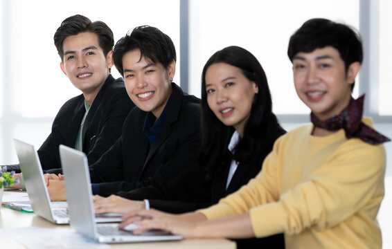 A group of multi-sex colleagues businesspeople, tomboy and transgender gay, working together with happy and intimate manner with laptop notebook computer in office
