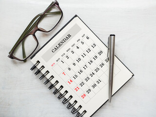 Blank notepad sheet and calendar for your congratulatory message. Closeup, top view. No people....