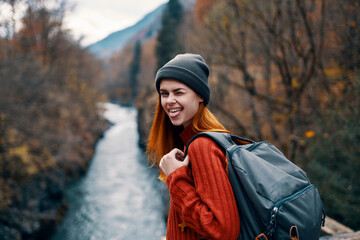 cheerful woman hiker in autumn clothes in the forest near the river