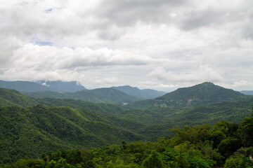 A beautiful mountain landscape with forest-covered peaks and cloudy skies.