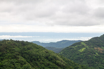 A beautiful mountain landscape with forest-covered peaks and cloudy skies.