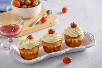 Tasty and fragrant cupcakes with strawberries and gentle cream on a white background
