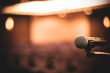 Microphone Public speaking backgrounds, Close-up the microphone on stand for speaker speech presentation stage performance with blur and bokeh light background.