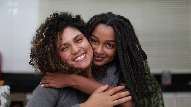 Mother and daughter smiling together. Girl embracing parent